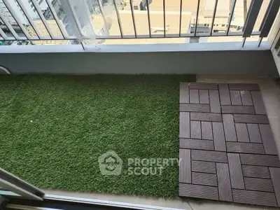 Charming balcony with artificial grass and wooden decking, perfect for relaxation.