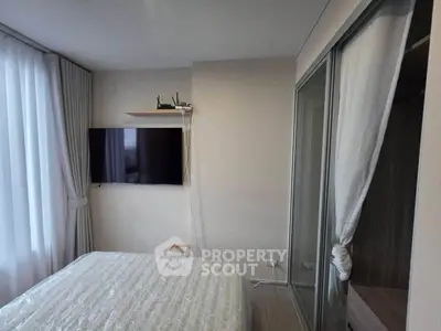Modern bedroom with wall-mounted TV and sliding closet doors in a cozy apartment.