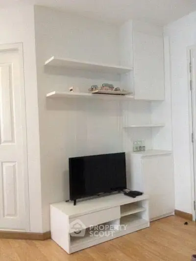 Modern living room with sleek white shelves and TV stand, showcasing minimalist design and functionality.