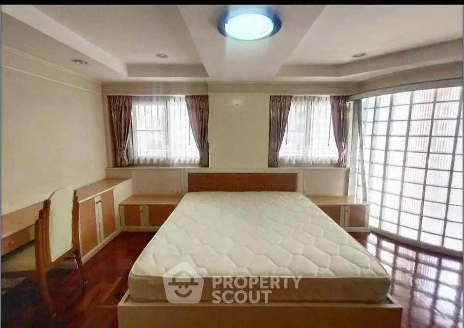 Spacious bedroom with large windows and built-in furniture, perfect for comfort and relaxation.