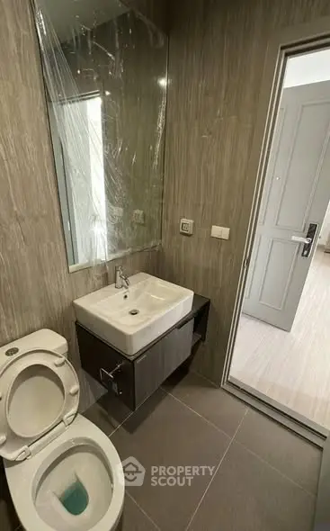 Modern bathroom with sleek sink and toilet, featuring elegant tile design.