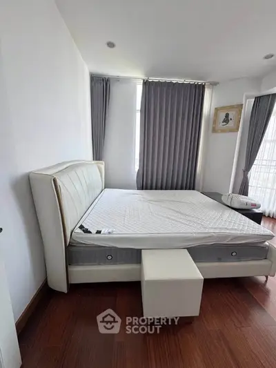 Spacious bedroom with modern decor and large windows for natural light.