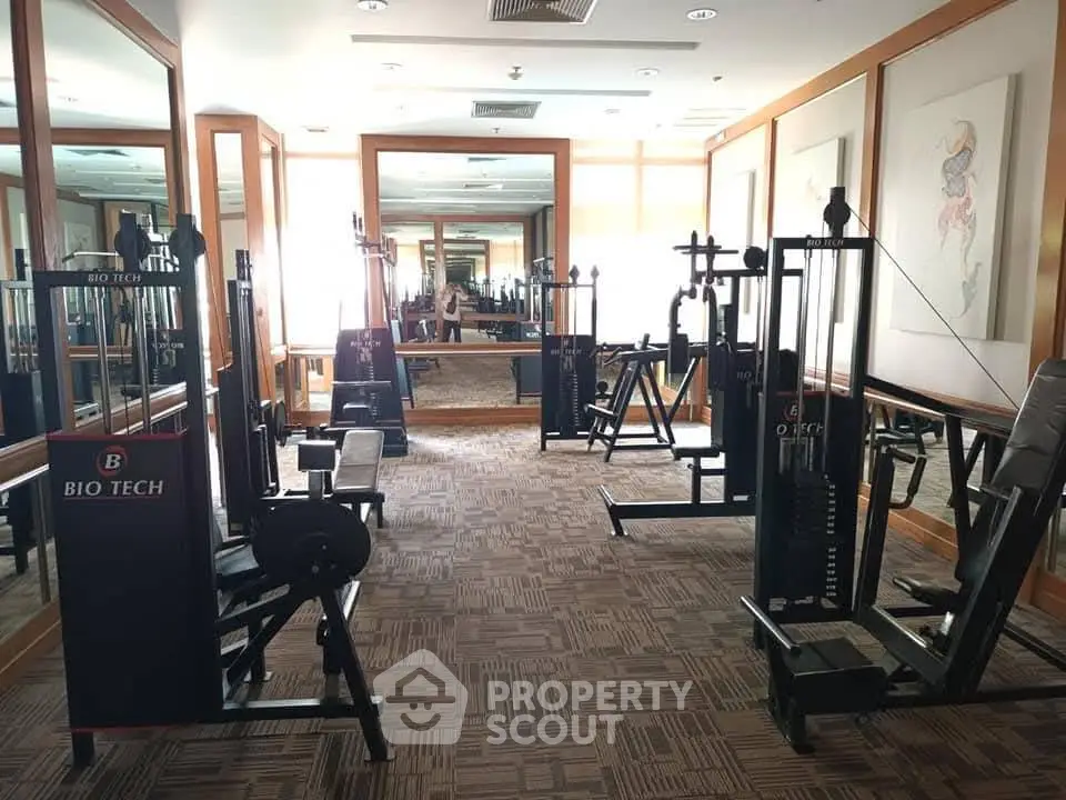 Spacious gym with modern fitness equipment and large mirrors in a residential building.