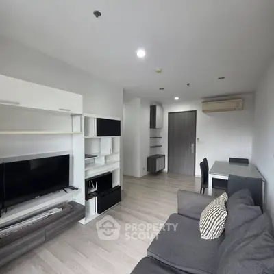Modern living room with sleek furniture and open layout, featuring a cozy sofa and entertainment center.