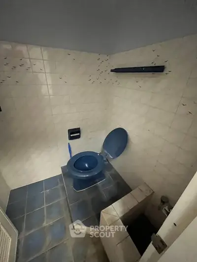 Unique blue-themed bathroom with elevated toilet and tiled walls, offering a distinctive design.