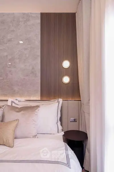 Elegant bedroom with modern lighting and luxurious bedding in a stylish apartment.