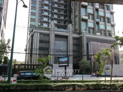 Modern high-rise building exterior with urban street view and lush greenery.