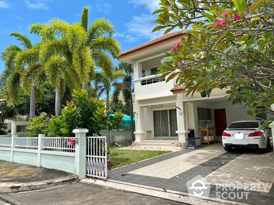 Charming two-story house with lush garden and driveway in tropical setting