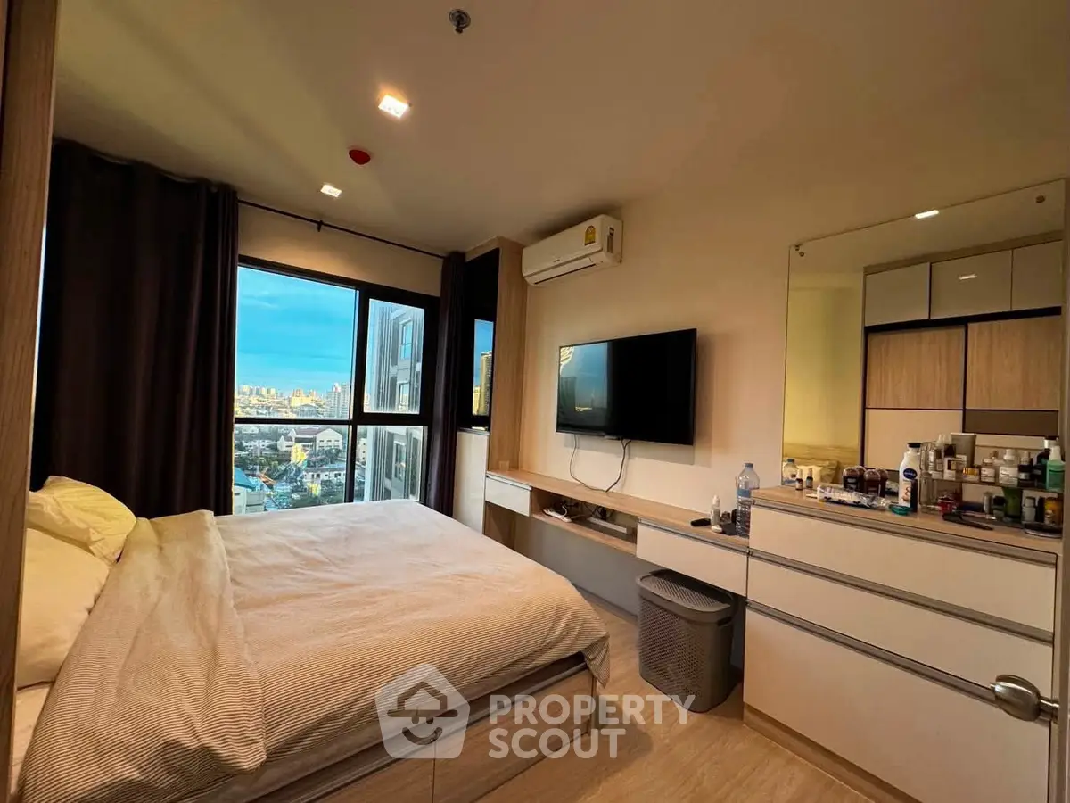 Modern bedroom with city view, featuring a wall-mounted TV and sleek storage solutions.
