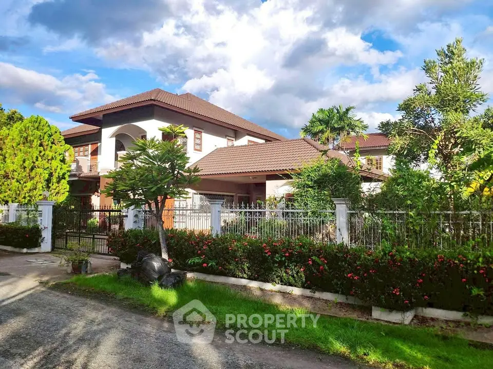 Stunning two-story house with lush garden and elegant architecture under a vibrant sky.