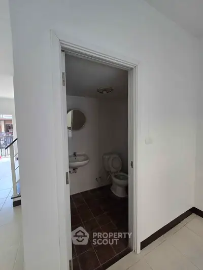 Compact bathroom with white fixtures and dark floor tiles in a modern apartment.