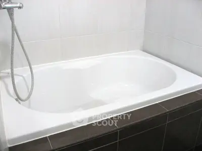Modern bathroom with sleek white bathtub and tiled walls, perfect for relaxation.