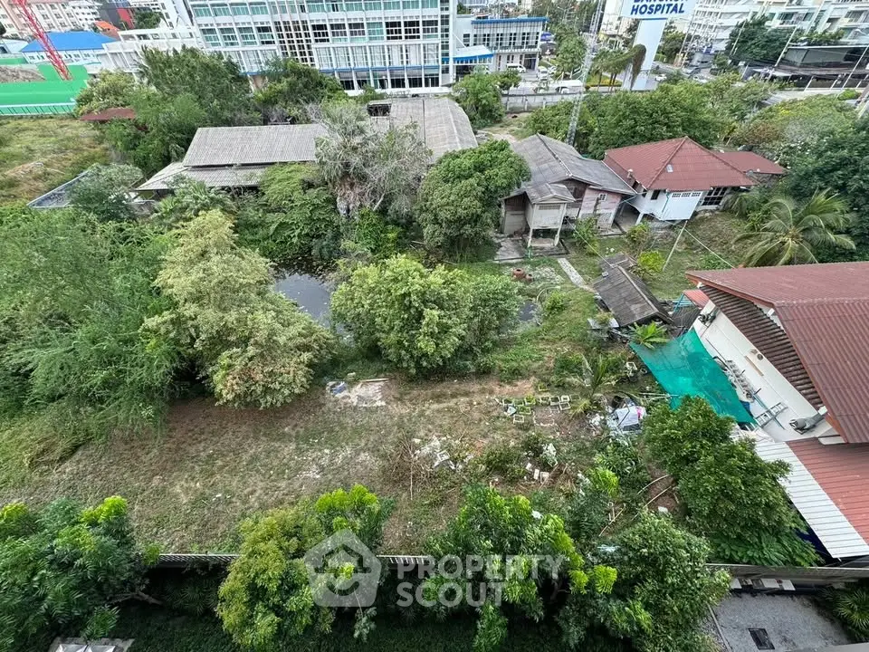 Aerial view of lush green residential area with traditional houses and trees, offering serene living environment.