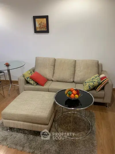 Cozy living room with modern beige sofa, stylish glass tables, and vibrant decor accents.