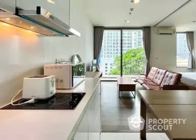 Modern open-plan living area with kitchen and city view balcony in high-rise apartment