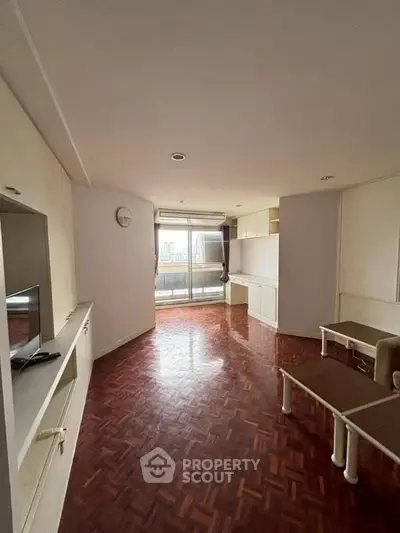 Spacious living room with parquet flooring and large windows offering city views.