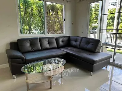Modern living room with sleek black leather sectional and glass coffee table.