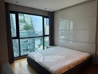 Modern bedroom with large window offering stunning city view in high-rise apartment.