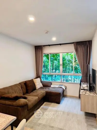 Cozy living room with large window and plush sofa, perfect for relaxation.