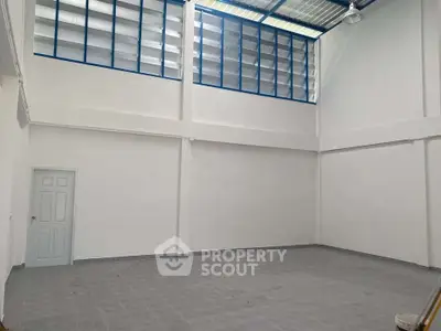 Spacious industrial-style room with high ceiling and large windows