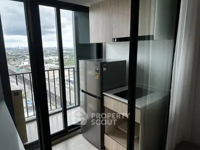 Modern compact kitchen with city view from high-rise balcony, featuring sleek appliances and stylish cabinetry.