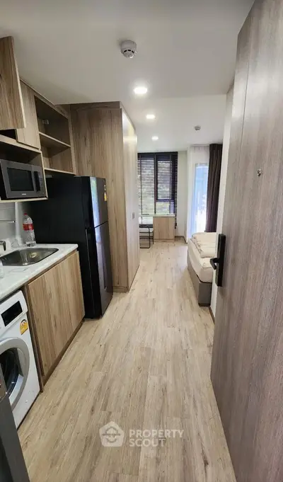 Modern studio apartment with wooden flooring and compact kitchen