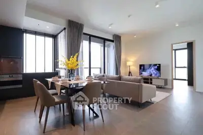 Spacious modern living room with open kitchen and elegant dining area, featuring large windows and stylish decor.