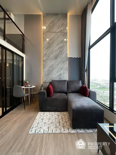 Modern living room with large windows and stylish decor in high-rise apartment.