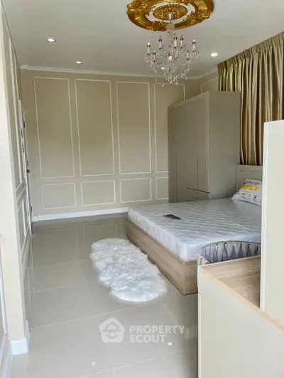 Luxurious bedroom with elegant chandelier and plush decor, featuring a cozy bed and stylish furnishings.