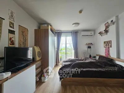 Cozy bedroom with modern decor, large window, and wooden flooring.