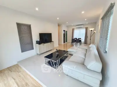 Spacious modern living room with sleek white sofa and elegant decor, perfect for relaxation and entertainment.