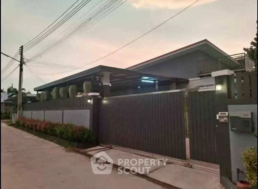 Modern single-story house with sleek design and gated entrance in a serene neighborhood.