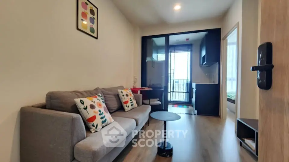 Modern living room with cozy sofa and open kitchen layout, featuring stylish decor and balcony access.