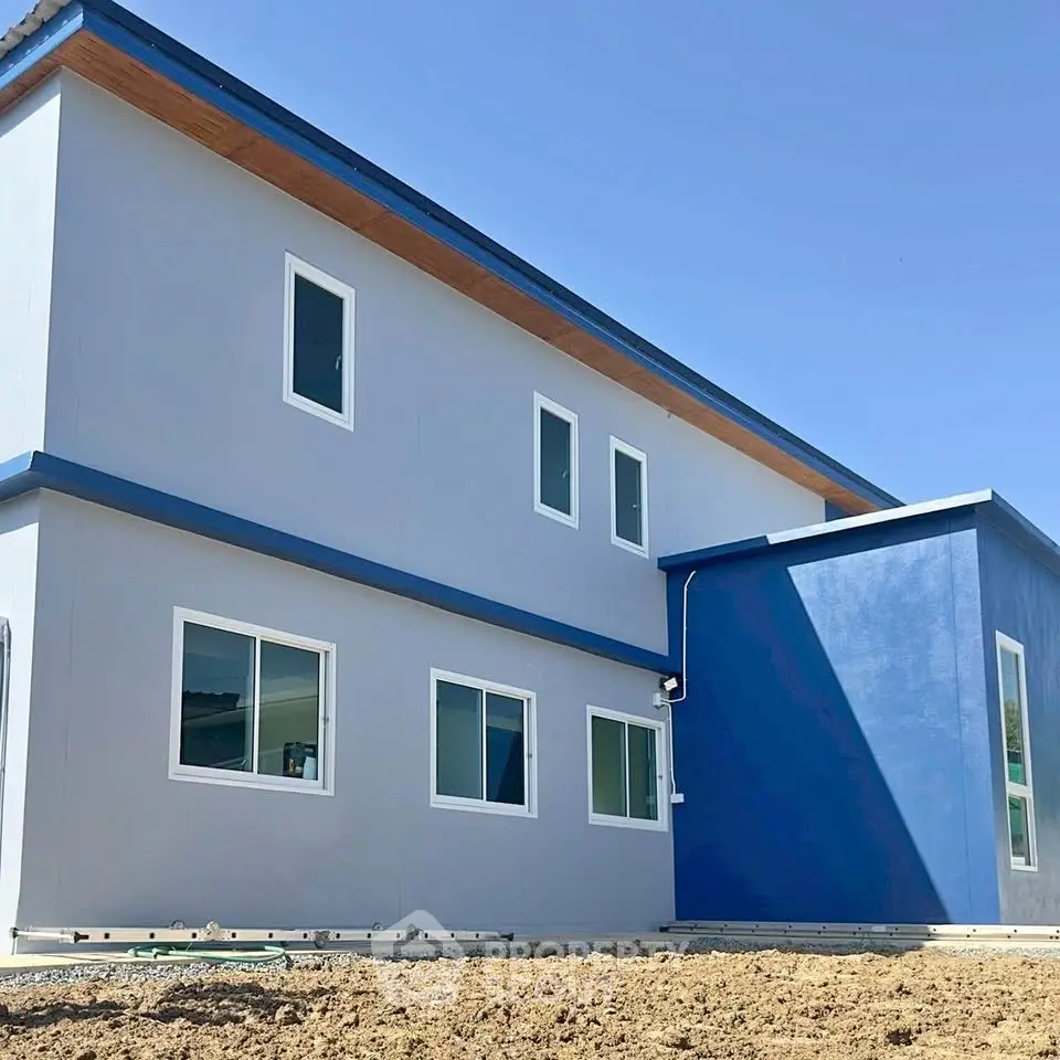 Modern two-story building with blue accents and large windows under clear sky.
