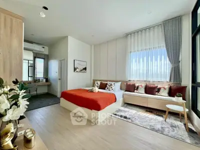 Spacious bedroom with large windows and modern decor, featuring a cozy seating area and stylish furnishings.