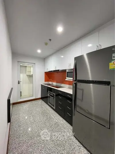 Modern kitchen with sleek appliances and granite flooring in a contemporary apartment.