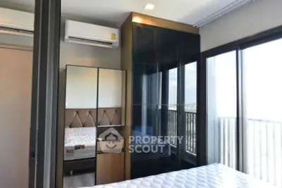 Modern bedroom with large windows and city view, featuring sleek furniture and air conditioning.