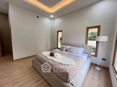 Spacious modern bedroom with elegant lighting and large windows in a luxury home.