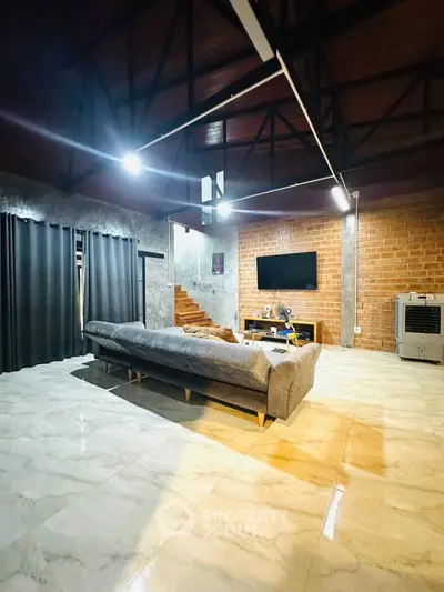 Spacious living room with modern design, exposed brick wall, and high ceiling beams.