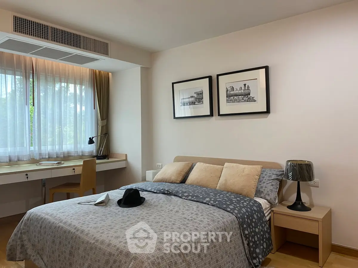 Cozy bedroom with stylish decor and natural light, featuring a comfortable bed and a work desk by the window.