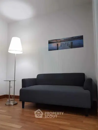 Modern living room with sleek gray sofa and stylish floor lamp on wooden flooring.