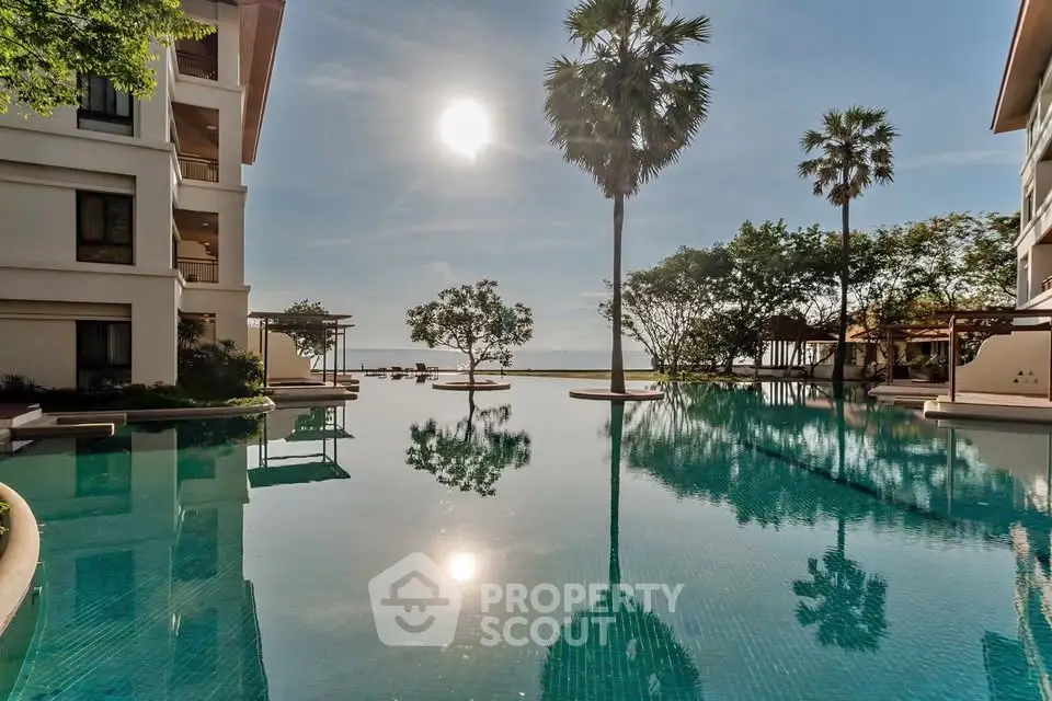 Luxurious resort-style pool with palm trees and ocean view, perfect for relaxation.