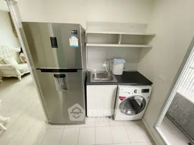 Modern kitchen with stainless steel fridge and washing machine, featuring sleek cabinetry and a compact design.