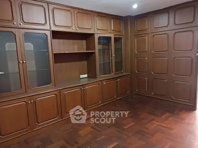 Spacious room with elegant wooden cabinetry and parquet flooring, perfect for a home office or study.