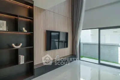 Modern living room with sleek TV setup and large window overlooking a private garden.