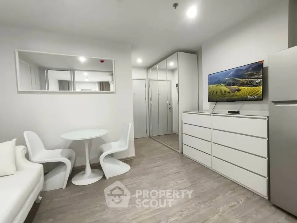 Modern living room with sleek white furniture and mirrored wardrobe