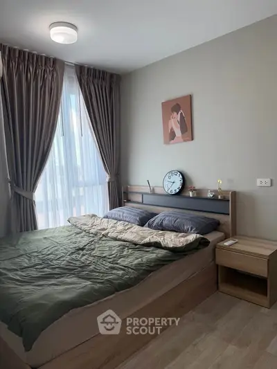 Cozy bedroom with modern decor and large window for natural light.