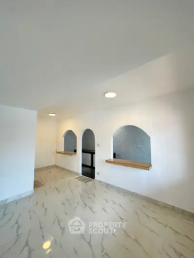 Spacious interior with elegant arches and marble flooring, perfect for modern living.