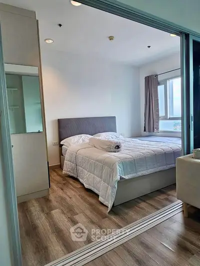 Cozy bedroom with modern decor and large window offering natural light.