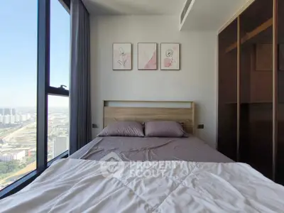 Cozy bedroom with city view, modern decor, and ample natural light.